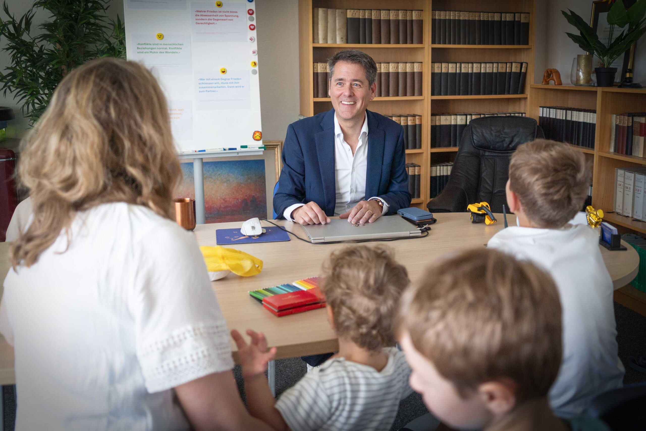 Familienrecht Mutter sitzt mit drei Kinder an Tisch von Anwalt, der aufklärt über Familienrecht